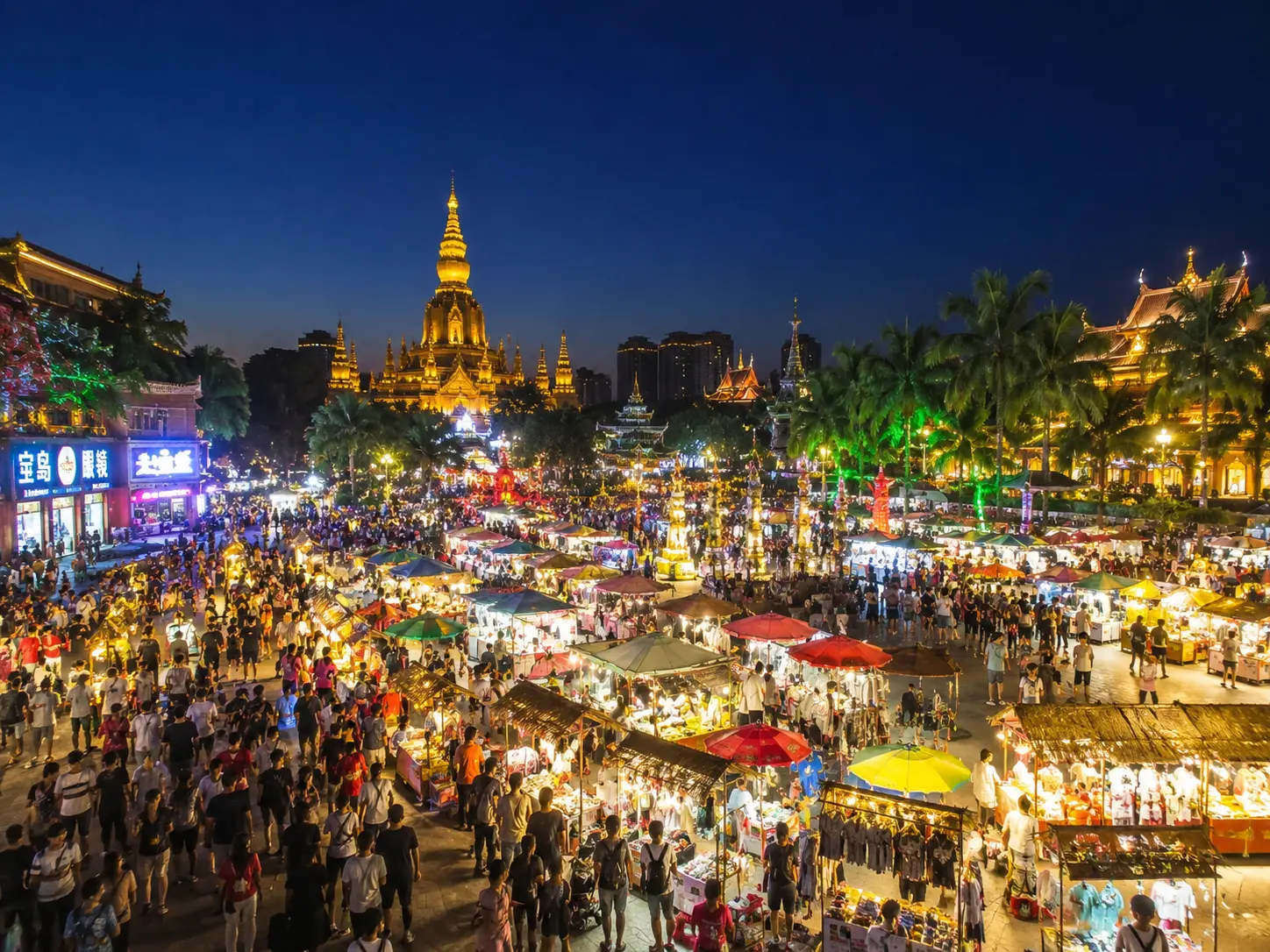 The golden towers and food stalls of the Gaozhuang night market in Jinghong, Xishuangbanna, lit up at night
